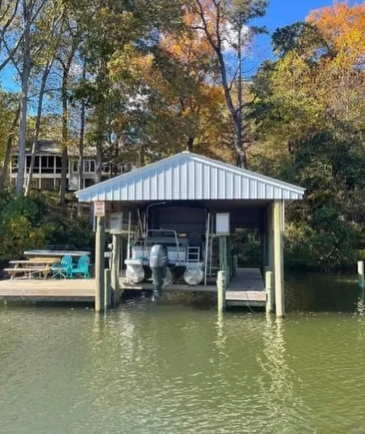 A boathouse with a white metal roof and a boat on the lift