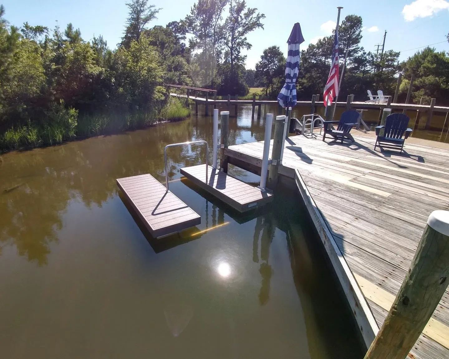 A floating kayak launch at the end of a pier on a creek