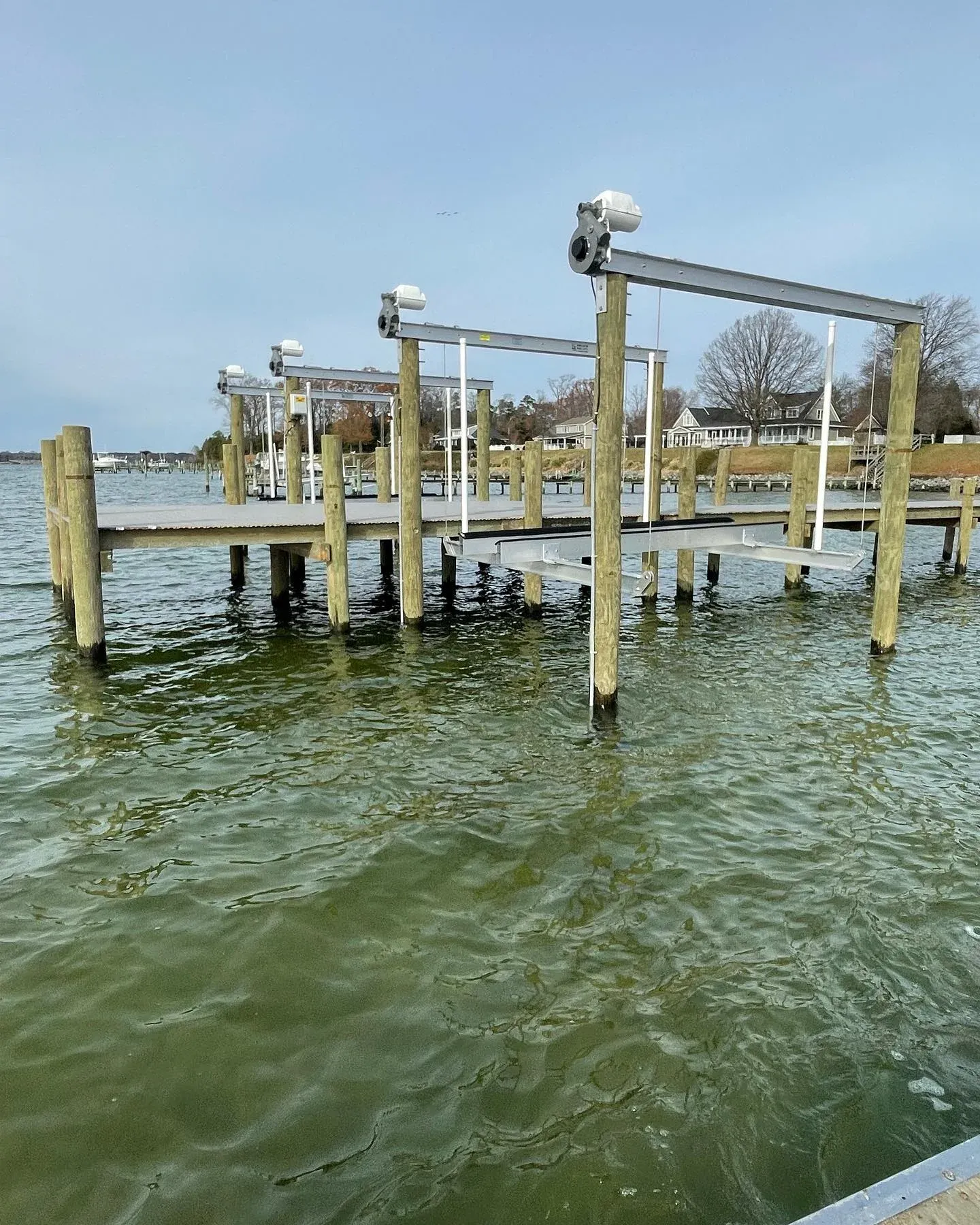 Two new boat lifts with motors on the pilings at the end of a long pier