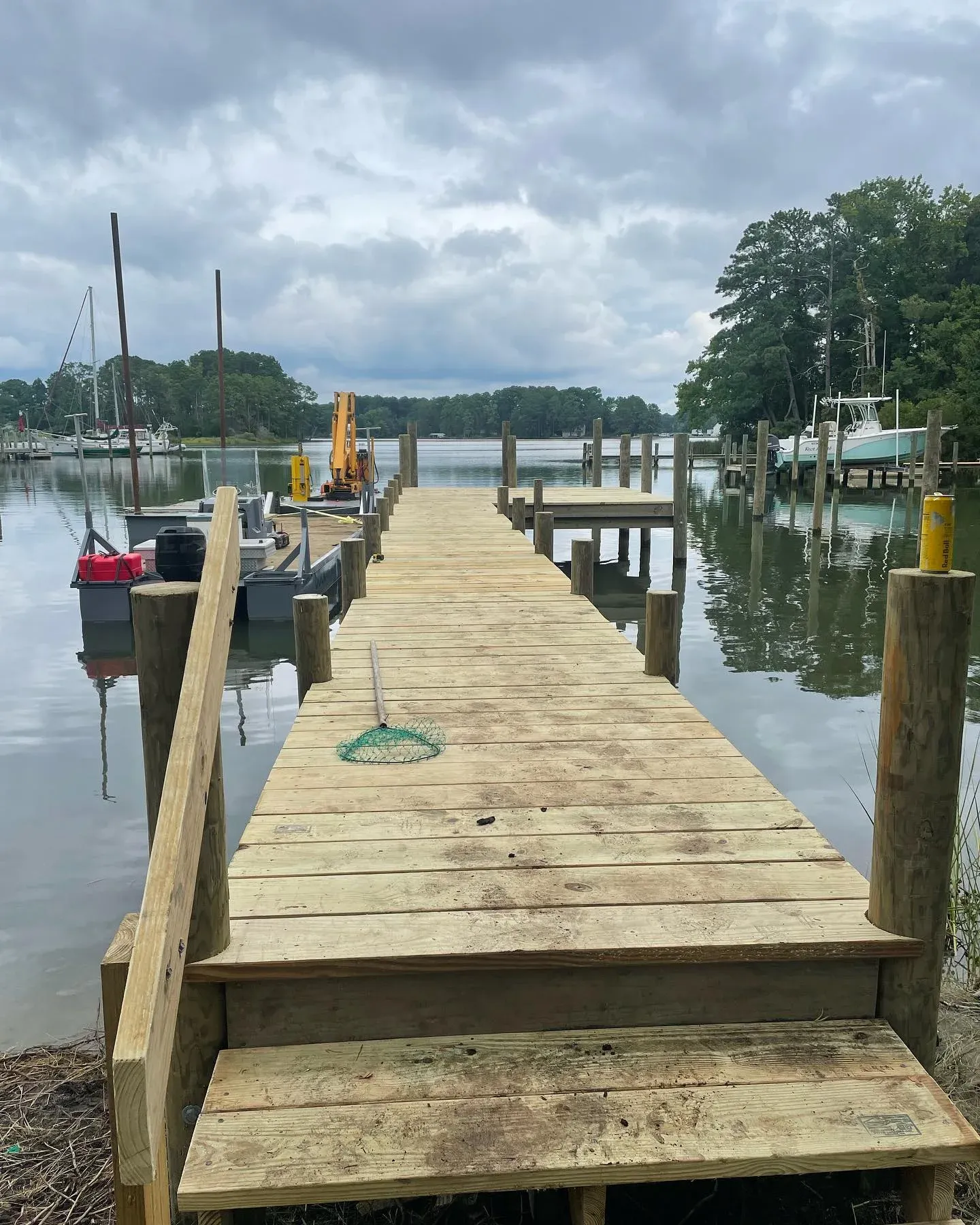 A new pier with steps down to the water, sailboats moored beyond